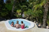Eine Familie im von Palmen umringten Pool auf dem Camping La Grainetière 