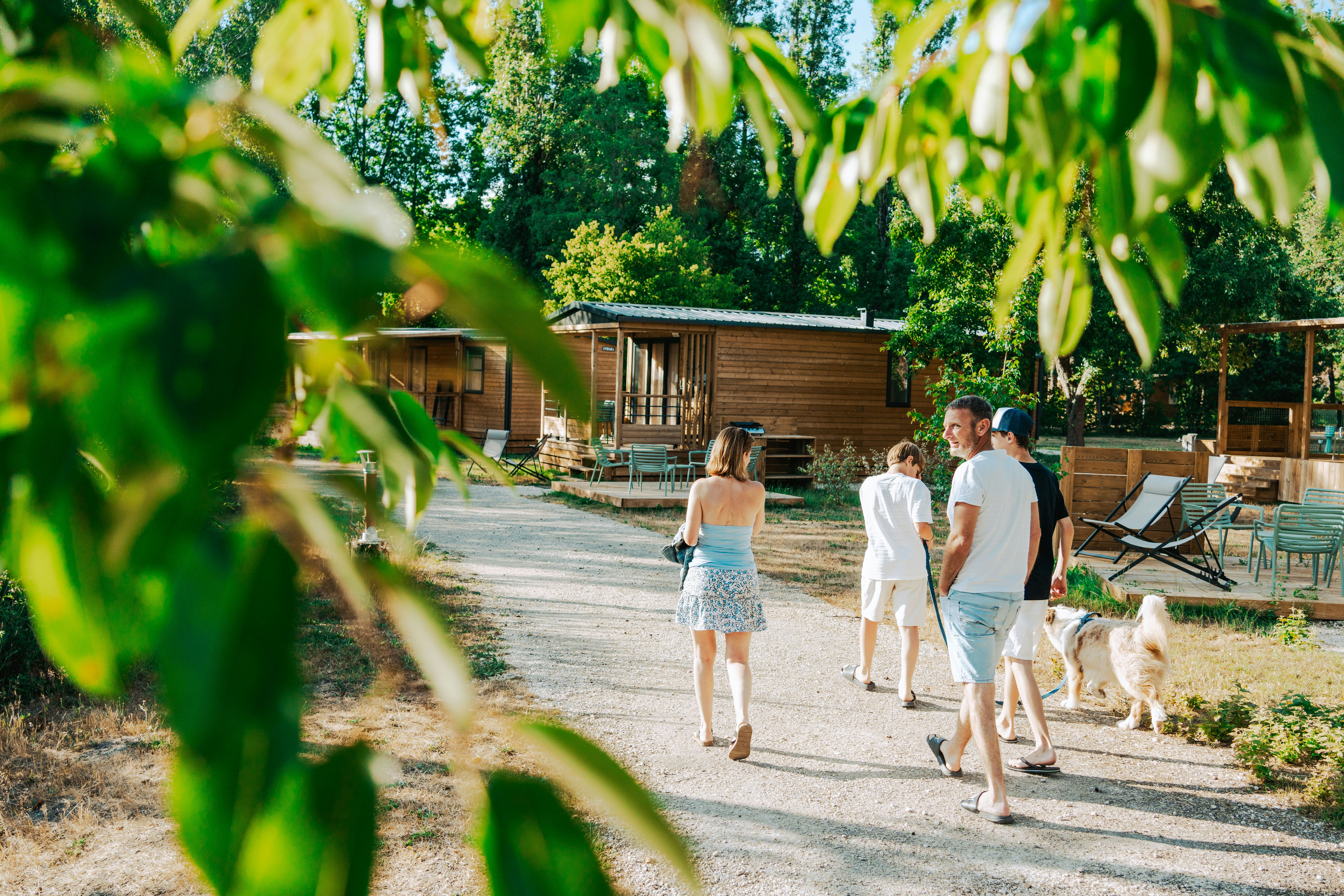 Camping La Grande Sologne - Familie mit Hund spaziert an den Mietunterkünften vorbei