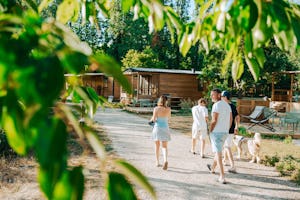Camping La Grande Sologne - Familie mit Hund spaziert an den Mietunterkünften vorbei