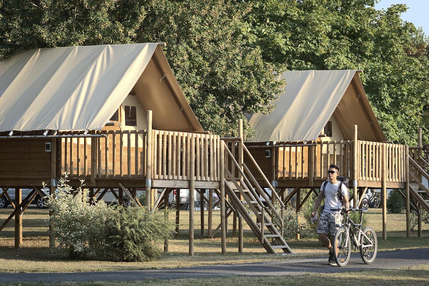 Camping La Gâtine  -  Camper mit Fahrrad auf dem Gehweg entlang der Mobilheime vom Campingplatz