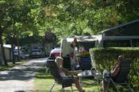 Camping La Isla - Picos de Europa - Gäste sitzen vor dem Mobilheim im Schatten der Bäume auf dem Campingplatz