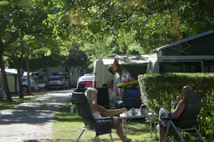 Camping La Isla - Picos de Europa - Gäste sitzen vor dem Mobilheim im Schatten der Bäume auf dem Campingplatz