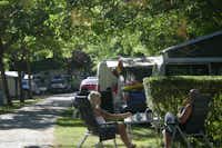 Camping La Isla - Picos de Europa - Gäste sitzen vor dem Mobilheim im Schatten der Bäume auf dem Campingplatz