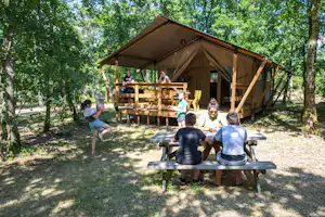 Camping La Peyrugue - Glamping-Zelt mit Terrasse umgeben von Bäumen