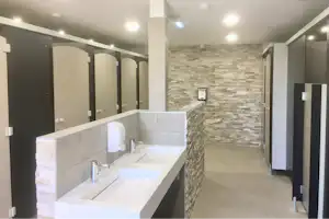 Camping La Plage de Treguer - Innenraum des Sanitärgebäudes mit Toilettenkabinen, Waschbecken und Spiegeln