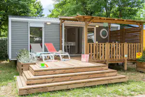 Camping La Plaine - Mobilheim vom Campingplatz mit Liegestühlen und Esstisch auf der Veranda