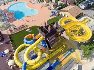 Wasserrutschen und gelber Wasserpark am Campingplatz, daneben Außenpool mit Liegen und Sonnenschirmen.