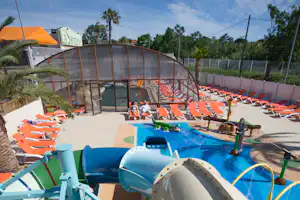 Camping la Sardane - Poolbereich vom Campingplatz mit Wasserrutsche, Indoor Pool, Kinderbecken und Liegestühlen in der Sonne