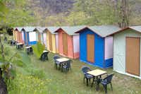 Camping La Sfinge - farbige Hütten mit Sitzgelegenheiten davor auf dem Campingplatz