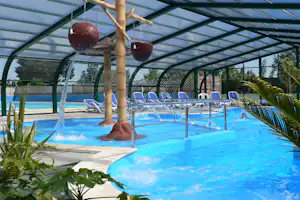 Überdachter Pool mit Wasserspiel, blauen Liegen und Sprudelwasser unter einem grünen Glasdach.