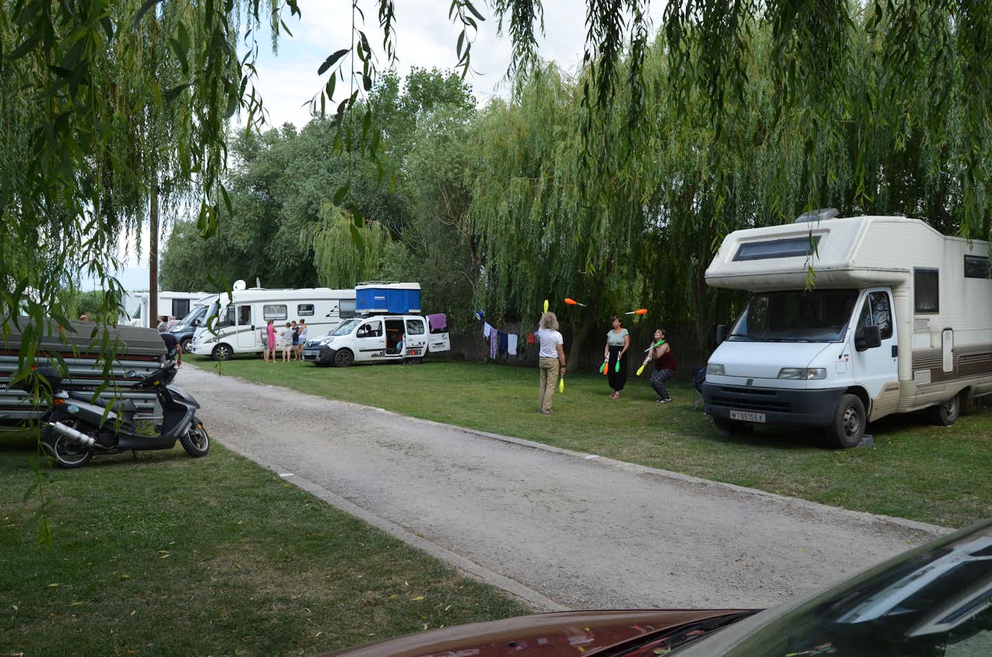 Camping Lac Murighiol - Gäste spielen vor dem Wohnmobil im Schatten der Bäume