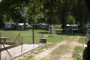 Campingplatz mit Stellplätzen für Wohnwagen und Wohnmobile, Rasenflächen, Bäume und ein Fußballtor auf dem Weg.
