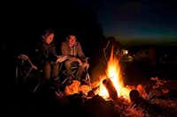 Camping Lazy - Camper sitzen an einem Lagerfeuer auf dem Campingplatz