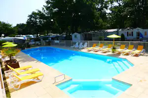 Camping-Pool mit türkisfarbenem Wasser, gelben Liegen und Sonnenschirmen, im Hintergrund Wohnwagen und Bäume.