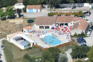 Camping Le Bois Joli - Vogelperspektive auf den Swimmingpool und die Gebäude des Campingplatzes mit Spielplatz an der Seite