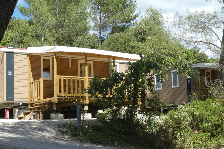 Camping Le Cezanne  Camping de Puyloubier - Mobilheime mit überdachten Terrassen umringt von Bäumen und Büschen 