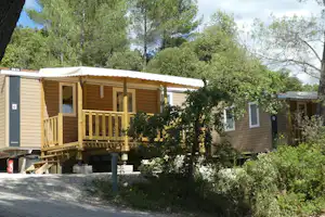 Camping Le Cezanne Camping de Puyloubier - Mobilheime mit überdachten Terrassen umringt von Bäumen und Büschen