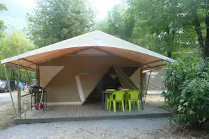 Campingzelt mit Veranda, Holzboden und grünen Stühlen, im Hintergrund Bäume und weitere Zelte auf dem Stellplatz.