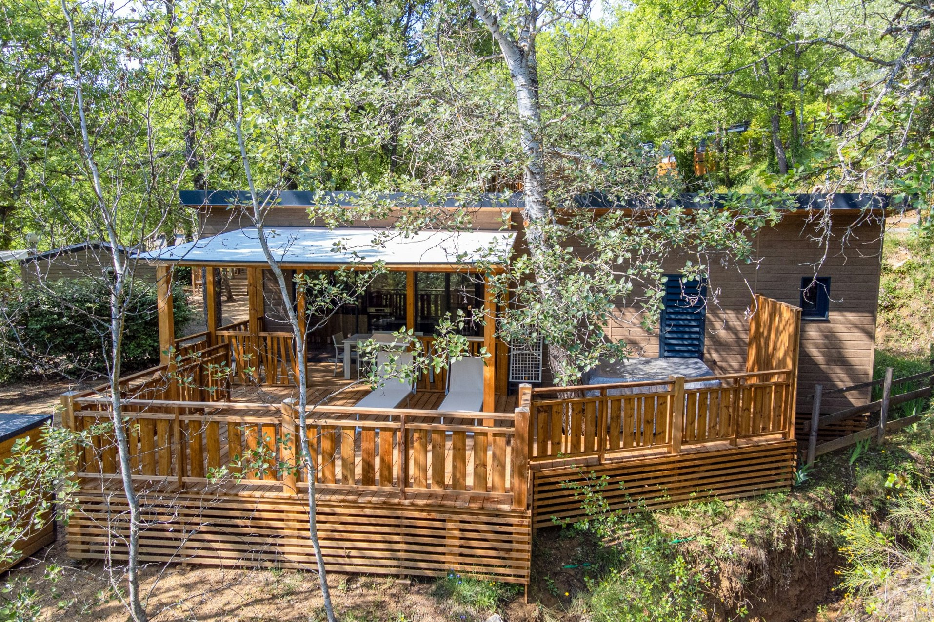 Camping Le Clos de Barbey  - Mobilheim mit Terrasse umgeben von Bäumen auf dem Campingplatz