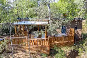 Camping Le Clos de Barbey - Mobilheim mit Terrasse umgeben von Bäumen auf dem Campingplatz