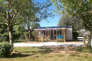 Camping Le Clos Lalande - Mobilheim auf dem Campingplatz mit überdachter Veranda zwischen Bäumen
