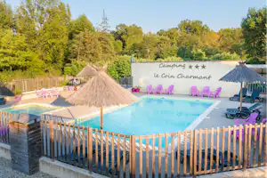 Camping Le Coin Charmant - Blick auf den Pool mit Liegestühlen und Sonnenschirmen
