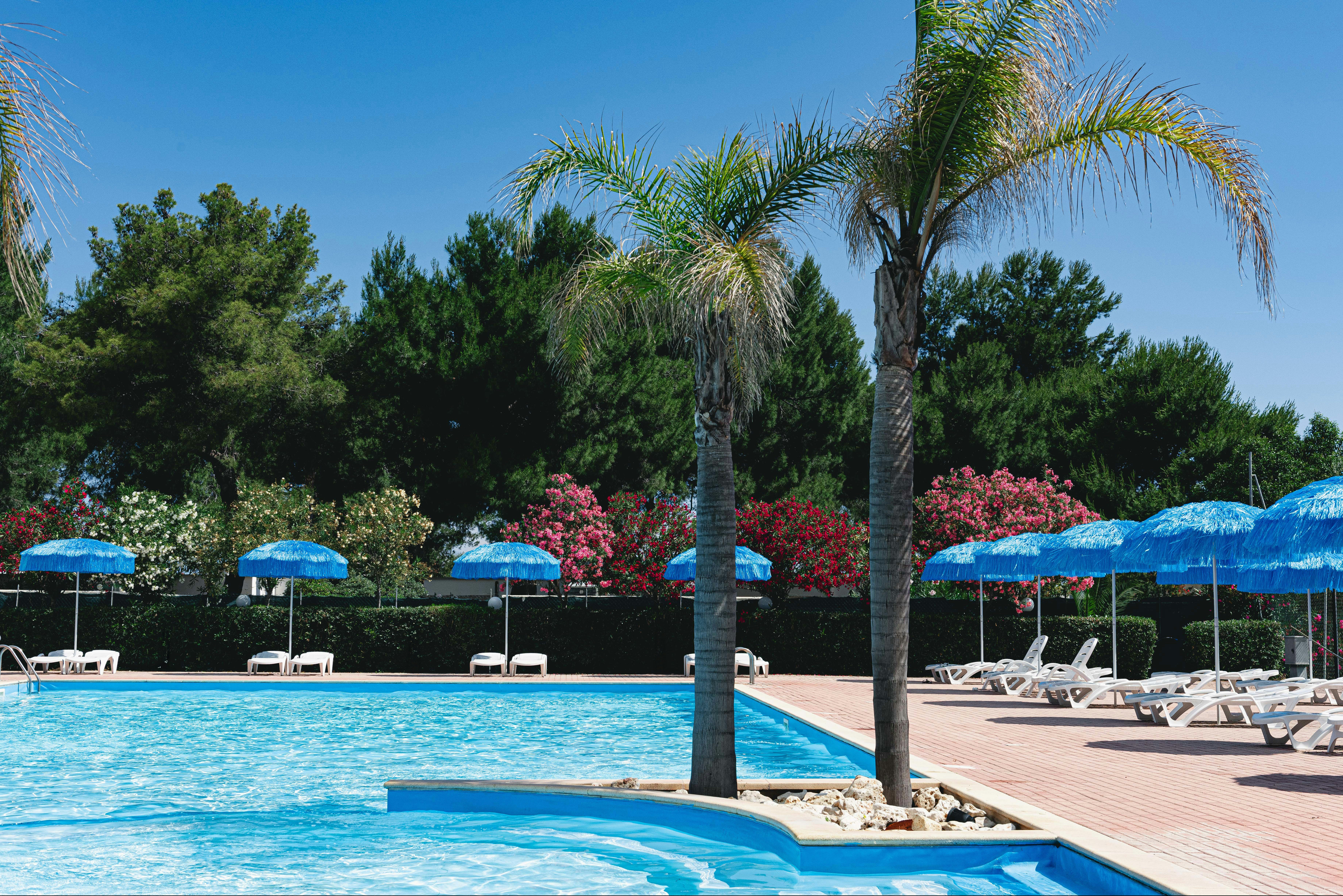 Camping Le Diomedee - Liegestühle mit Sonnenschirmen am Pool