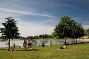 Camping Le Domaine de Louvarel - Liegewiese und Spielplatz am See Ruisseau de l'Étang de Semon vom Campingplatz