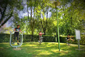 Camping Domaine de Mépillat - Gäste des Campingplatzes an den Outdoor-Fitness-Geräten auf einer Wiese des Campingplatzes