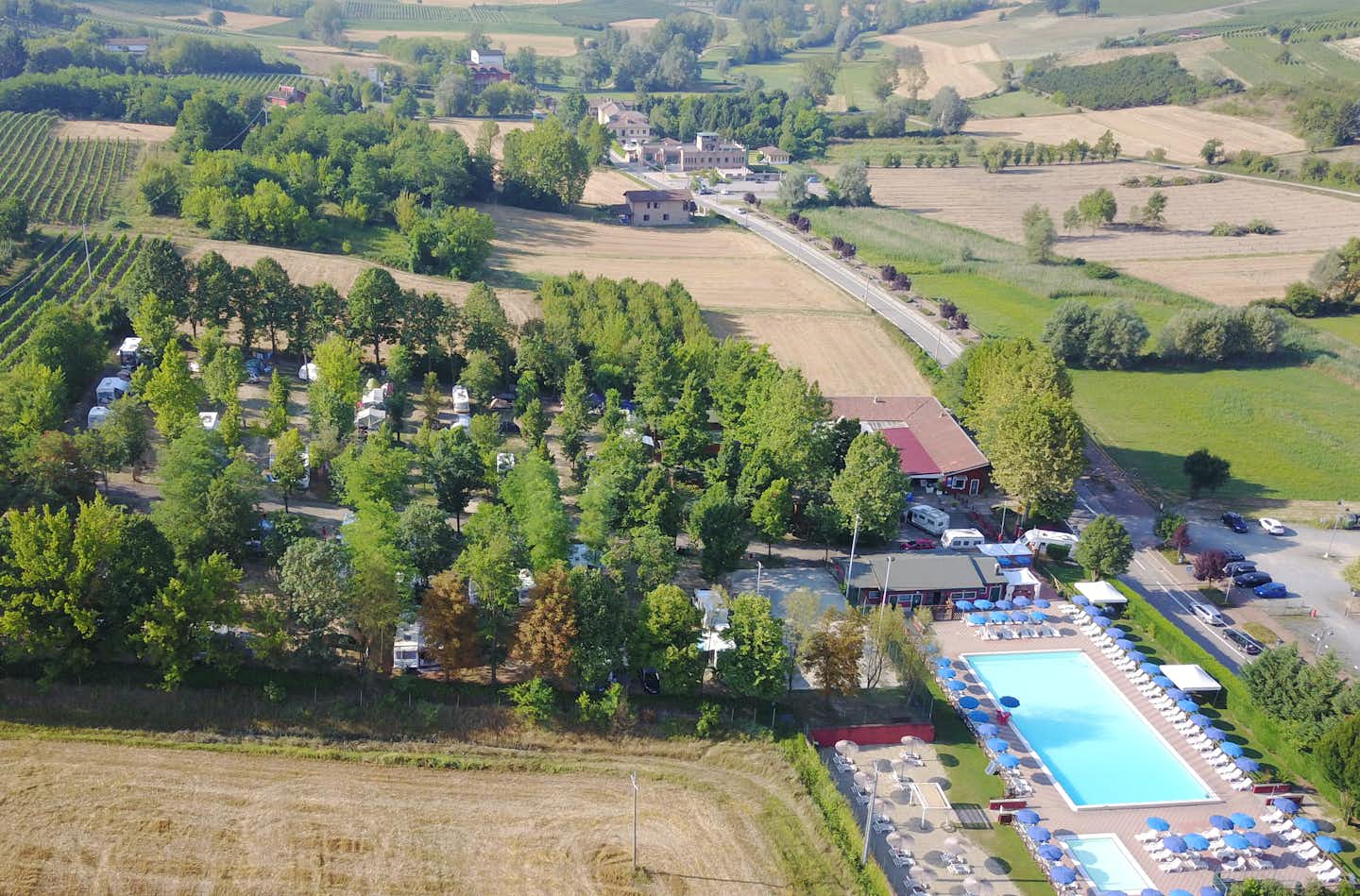 Camping Le Fonti - Vogelperspektive auf den Campingplatz mit Stellplätzen und Swimmingpools, im Hintergrund die hügelige Natur der Region Emilia-Romagna