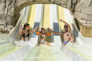 Familie im Wasser eines Spa-Bads in einer Zeltkabine mit großen Vorhängen und Steinmauer im Hintergrund.