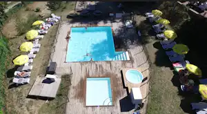 Großer Camping-Pool mit Liegen und Sonnenschirmen, daneben ein kleineres Becken, umgeben von Rasen und Wegen.