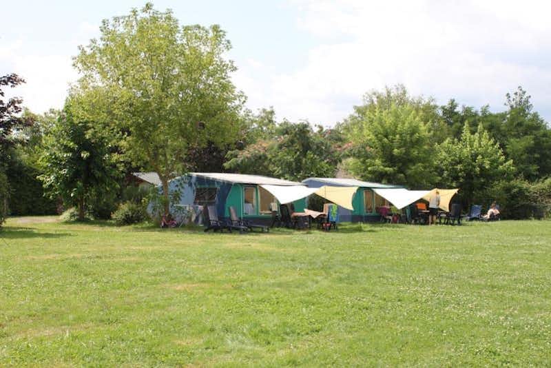 Camping Le Mondou - Wohnwagen- und Zeltstellplatz vom Campingplatz auf einer Wiese zwischen Bäumen 