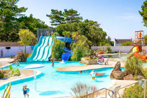 Familienpool mit Wasserrutsche, Kinderbecken und Liegestühlen im Garten mit Bäumen und Sträuchern.
