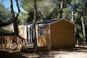 Camping Le Pastory - Mobilheim vom Campingplatz mit Veranda zwischen Bäumen