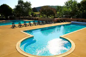 Rundes Camping-Poolbecken mit Sprudelbereich, umgeben von Terrassenboden und mehreren Liegen, im Hintergrund Bäume und Hecken.