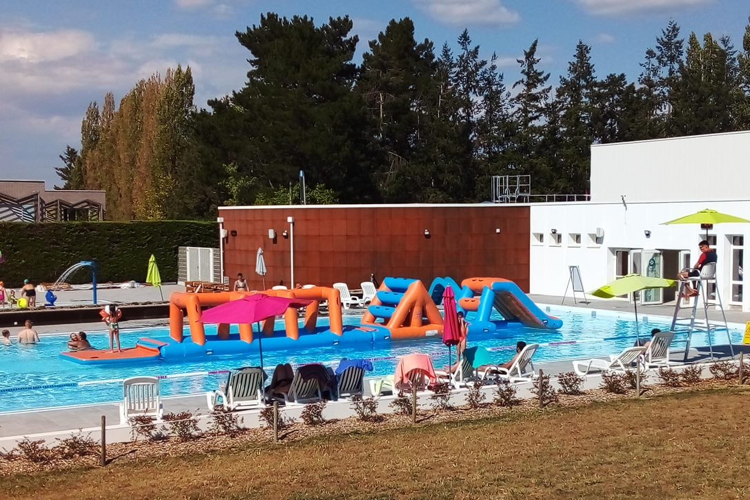 Camping le Petit Bocage - beaufsichtigter Außenpool mit schwimmenden Wasserparcours für Kinder und Liegestühle sowie Sonnenschirme am Beckenrand