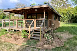 Camping des Tourbières Holz-Chalet Mietunterkunft -Zen- mit überdachter Veranda und Sitzmöglichkeiten