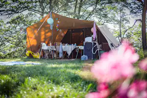 Camping Le Plô - Zelt auf dem Stellplatz mit überdachtem Bereich im Freien und Sitzgelegenheiten