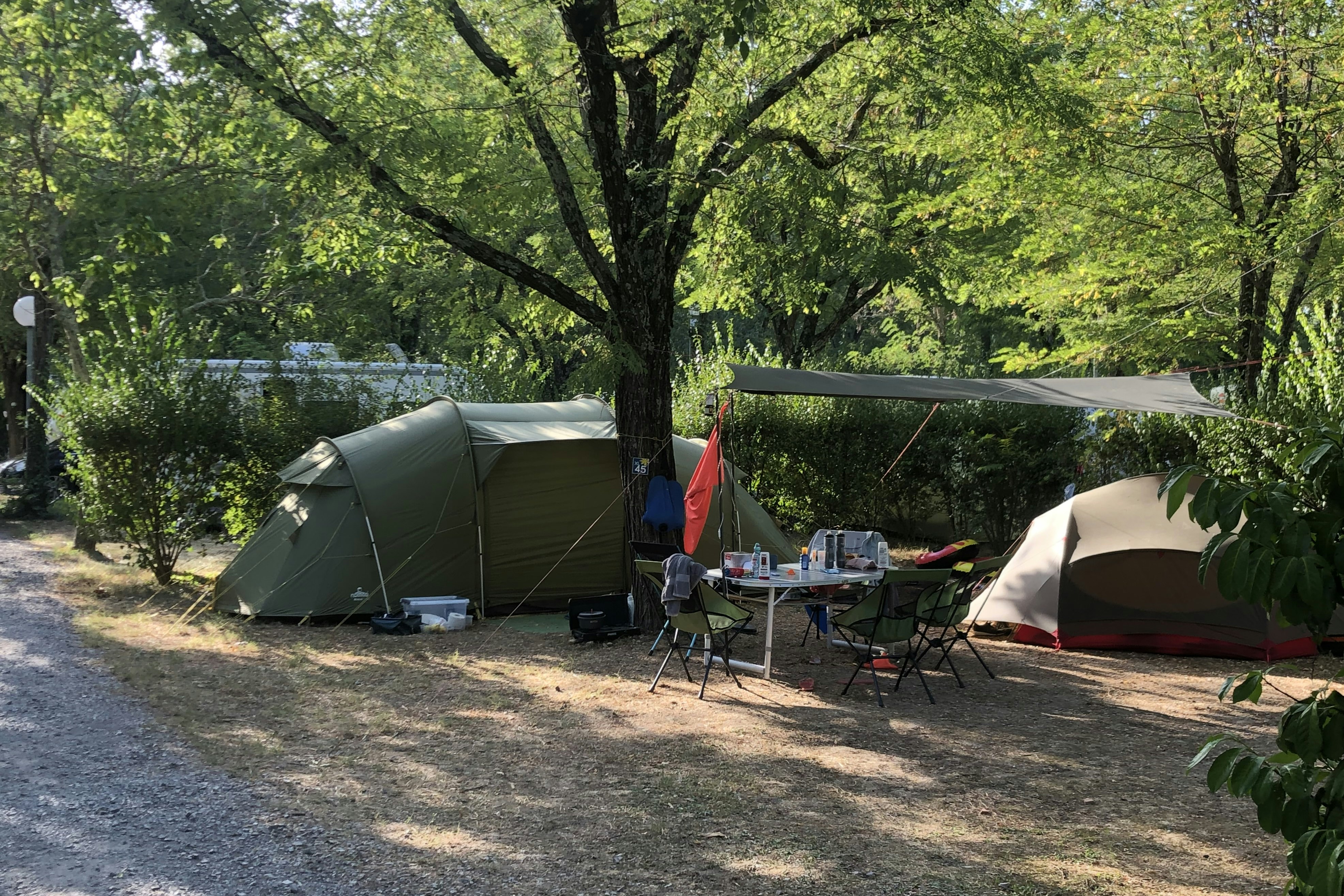 Camping Le Plan d'Eau - Standplätze zwischen den Bäumen auf dem Campingplatz