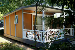 Camping Le Péquelet - Mobilheim mit Terrasse zwischen Bäumen auf dem Campingplatz