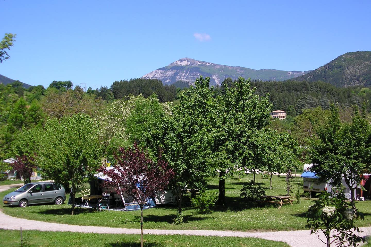 Camping Le Riou-Merle - Wohnwagen- und Zeltstellplatz zwischen Bäumen mit den Alpen im Hintergrund