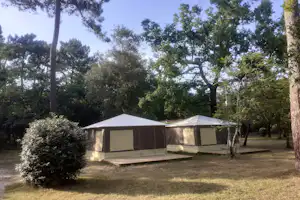 Camping Le Royannais Zelt-Bungalows mit kleiner Terrasse im Grünen, teilweise unter Bäumen im Halbschatten