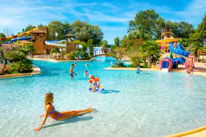 Großes Schwimmbecken auf dem Campingplatz mit Rutsche, Spielbereich und mehreren Kindern im Wasser.