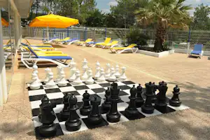 Camping Le Saint Martin - Schach am Pool vom Campingplatz mit Sonnenschirmen und Liegestühlen