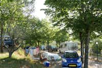 Camping Le Soline   -  Wohnwagen- und Zeltstellplatz zwischen Bäumen auf dem Campingplatz