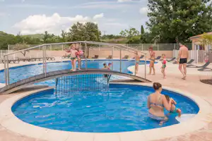 Großes Camping-Schwimmbecken mit Geländer, mehrere Kinder und Erwachsene im Wasser sowie Liegen am Rand.