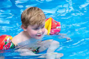 Kleines Kind im Schwimmbecken mit Schwimmring, planscht im Wasser.