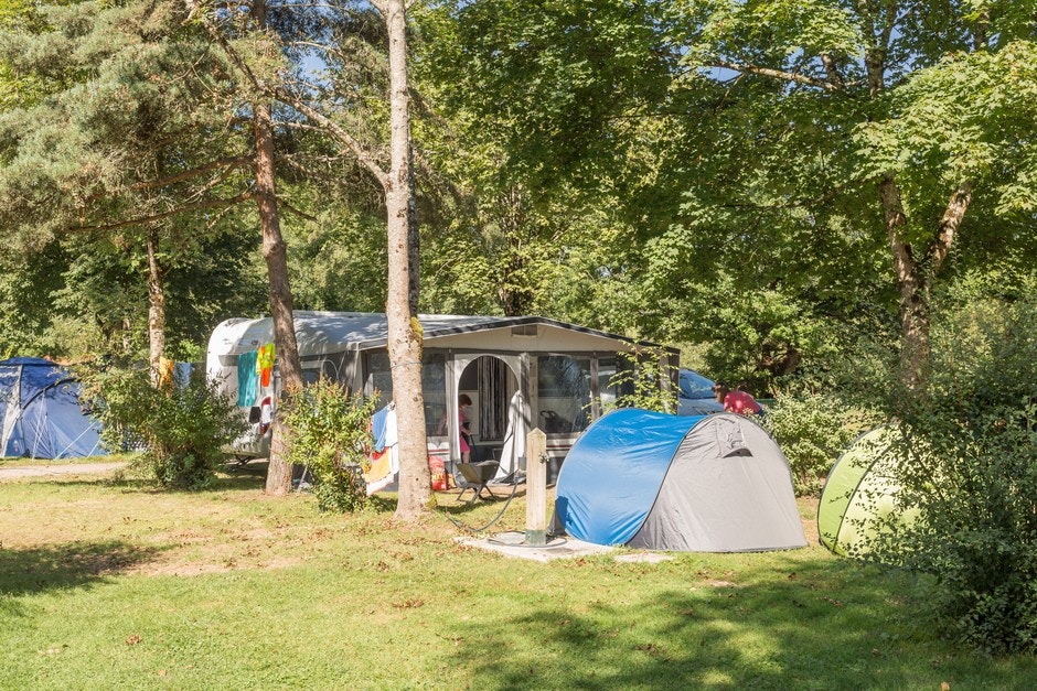 Camping Le Val de Bonnal  -  Wohnwagen- und Zeltstellplatz zwischen Bäumen auf dem Campingplatz