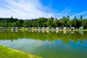 Camping Le Val de l'Aisne - Wohnwagenstellplätze im Schatten der Bäume mit Blick auf den See